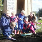 Young children digging with trowels with two young mums