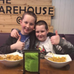 Two lads with thumbs up and bowls of food