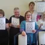 Five adults with learning disabilities holding up info sheet