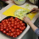 Woman chopping lettuce and tomatos