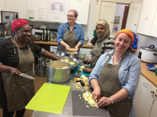 Four women cooking in community kitchen